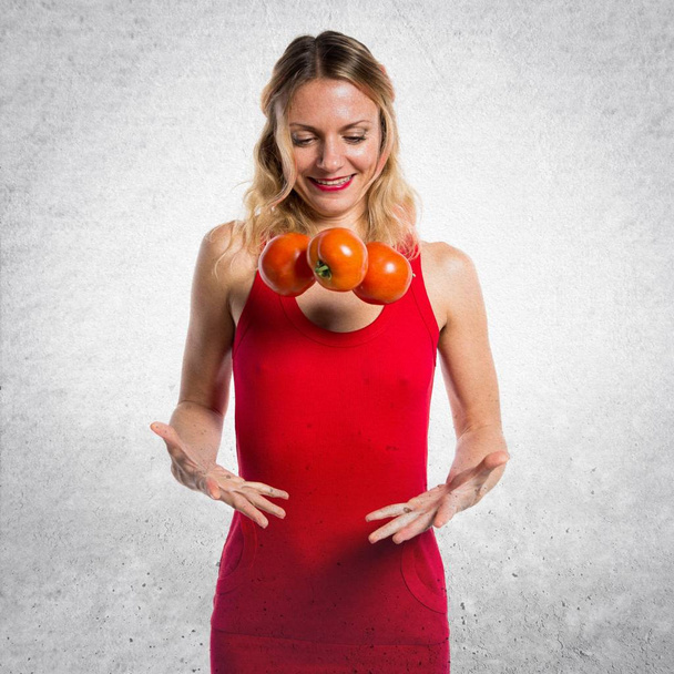 schöne blonde Frau hält Tomaten auf strukturiertem Hintergrund - Foto, Bild