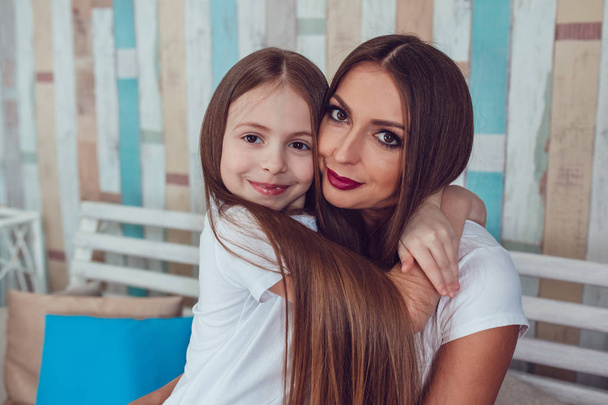Mom and daughter with beautiful long hair are sitting in embrace. - Valokuva, kuva
