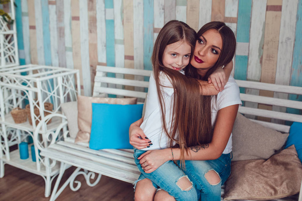Mom and daughter with beautiful long hair are sitting in embrace. - Foto, Bild