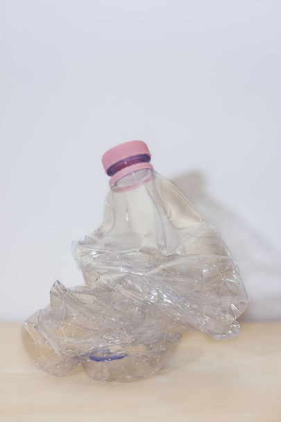 Смятая пластиковая бутылка на деревянном полу
 - Фото, изображение
