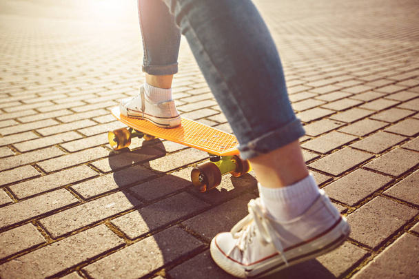 Bokovky dívka s skateboard venku. Closeup skateboardingu. Aktivní sportovní žena baví v parku - Fotografie, Obrázek