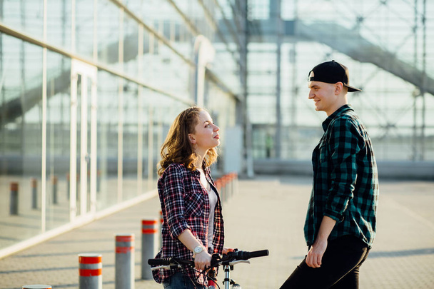 Attractive couple, baldheaded man and charming hipster woman meeting behind the modern terminal of airport. Sport, healt life and holiday concept. - Photo, image