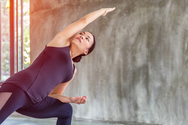 Asian trainee strong woman practicing difficult yoga pose in a concrete background - Foto, Bild