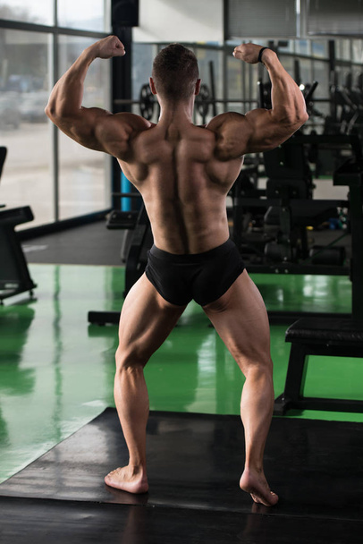 Muscular Man Flexing Back Muscles Pose - Foto, afbeelding