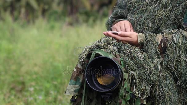 ornithologist in the ghillie suit using smartphone  - Footage, Video