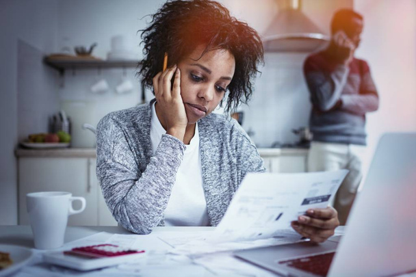 Young African american couple facing financial problem and not able to pay out debts. Desperate female holding hand on her cheek, feeling stressed while managing family budget at kitchen table - Фото, зображення