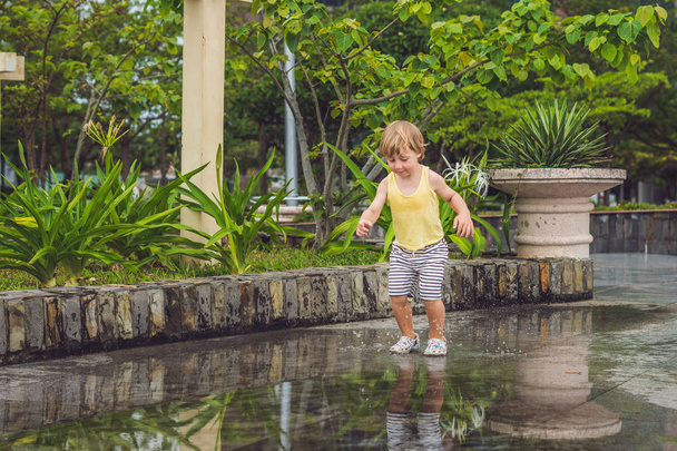 Little boy runs through a puddle.  - Foto, afbeelding