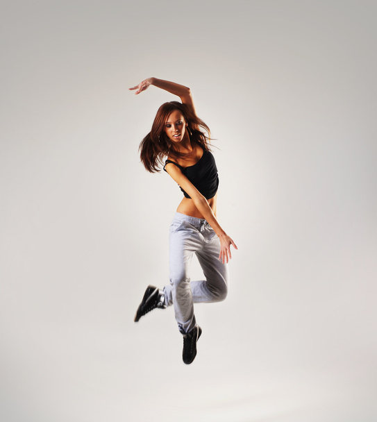 Young and sexy modern dancer over grey background - Фото, изображение