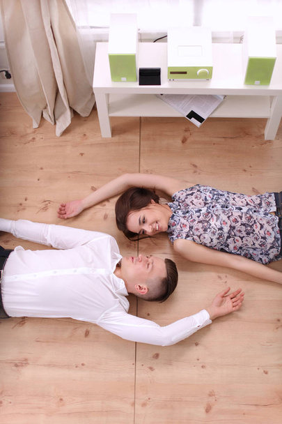 Happy young couple lying together on the floor - Foto, afbeelding