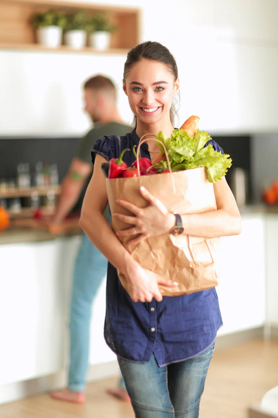 Молодая пара на кухне, женщина с пакетом покупок - Фото, изображение