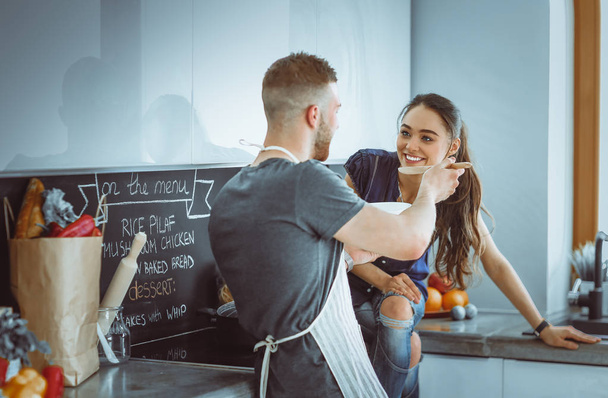 Couple cooking together in their kitchen at home - Фото, зображення