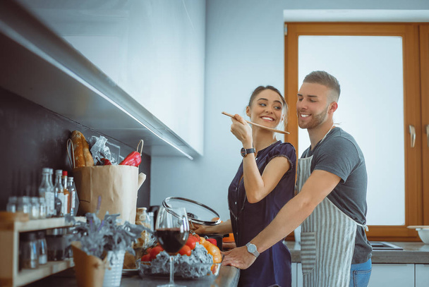 Couple cooking together in their kitchen at home - Foto, afbeelding
