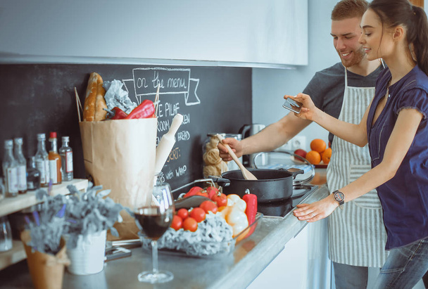 Couple cooking together in their kitchen at home - Фото, зображення