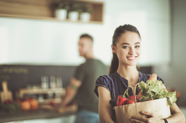 Young couple in the kitchen , woman with a bag of groceries shopping - Photo, Image