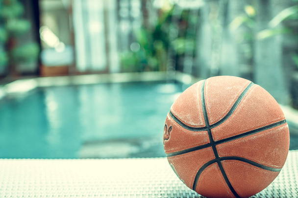 Bola de basquete em um fundo de piscina, cena esportiva tropical
. - Foto, Imagem