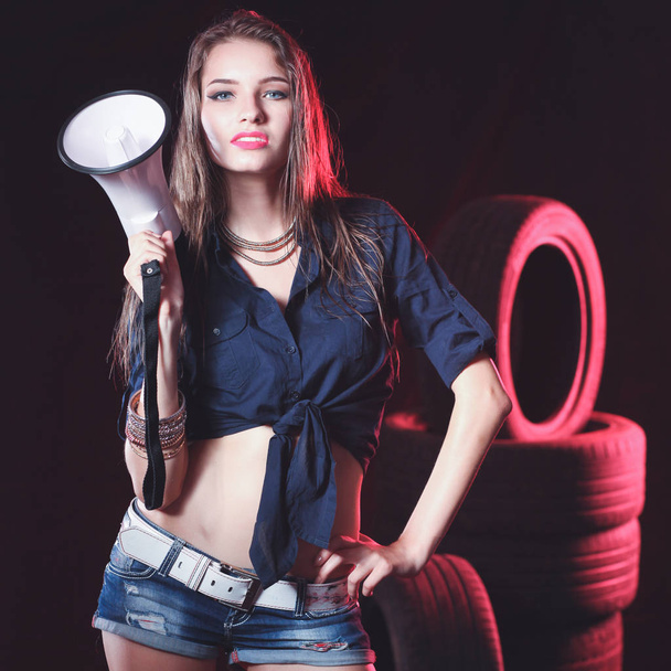 Portrait of young woman standing in the old garage. isolated on black background - Photo, image