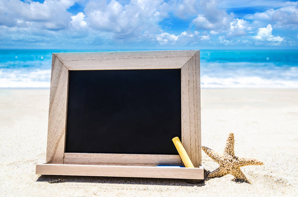 Czarna tablica drewna z rozgwiazdy i kredy na piaszczystej plaży - Zdjęcie, obraz