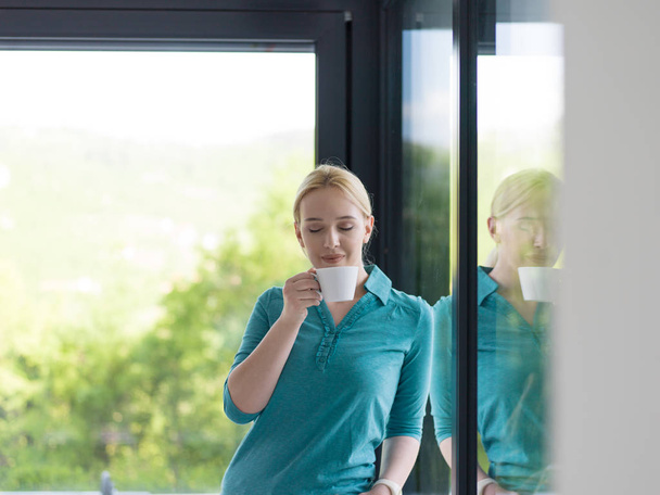 young woman drinking morning coffee by the window - Foto, afbeelding