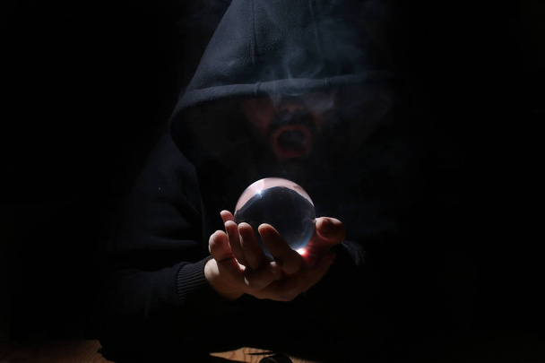 az ember egy fekete csuklya a kristály labda - Fotó, kép