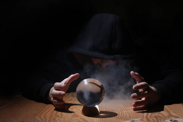 ο άνθρωπος σε μια μαύρη κουκούλα με μπάλα cristal - Φωτογραφία, εικόνα