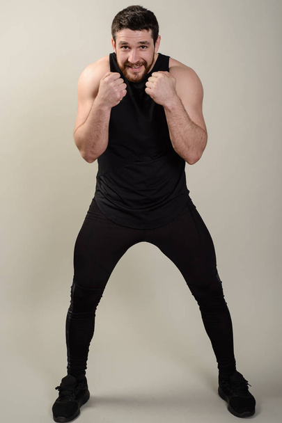 El luchador está en una pose de protección frontal contra un fondo gris
 - Foto, imagen