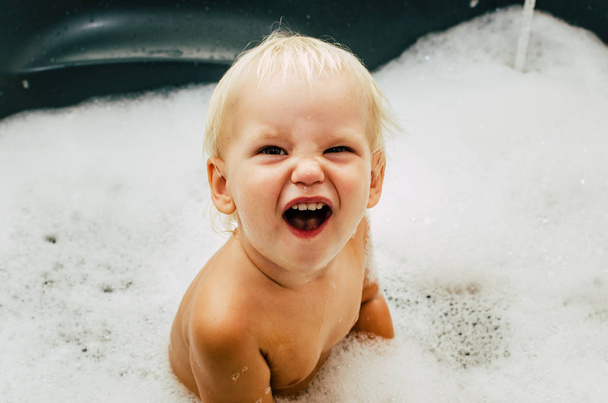 The child is bathing. The bath is full of foam - Fotó, kép