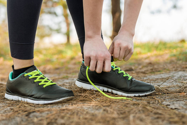 Une fille en pantalon de sport et un sweat à capuche, debout attaché sa chaussure
 - Photo, image