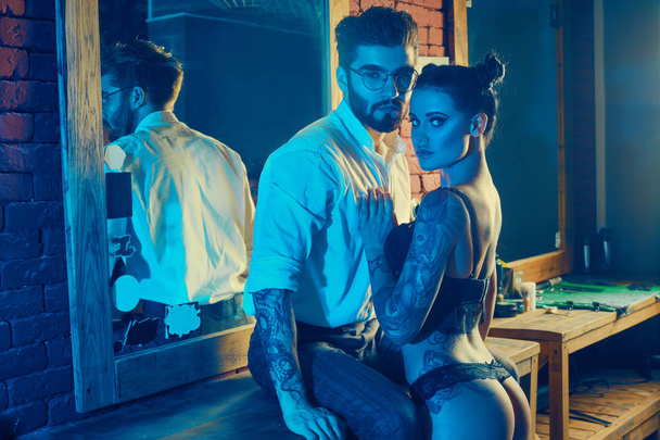 Жестокий мужчина в элегантном костюме и сексуальная девушка с татуировкой
 - Фото, изображение