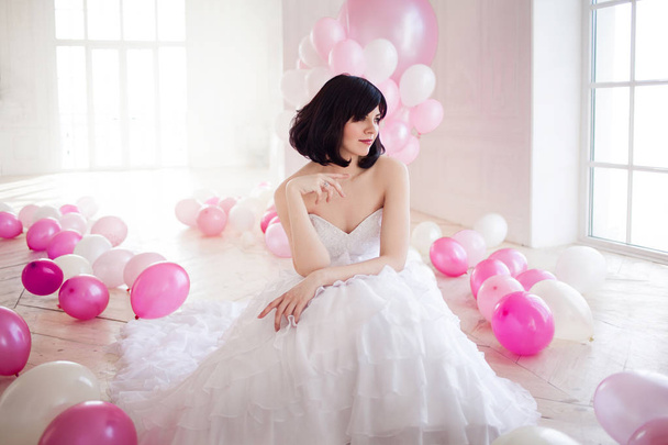 Young woman in wedding dress in luxury interior with a mass of pink and white balloons. - Φωτογραφία, εικόνα