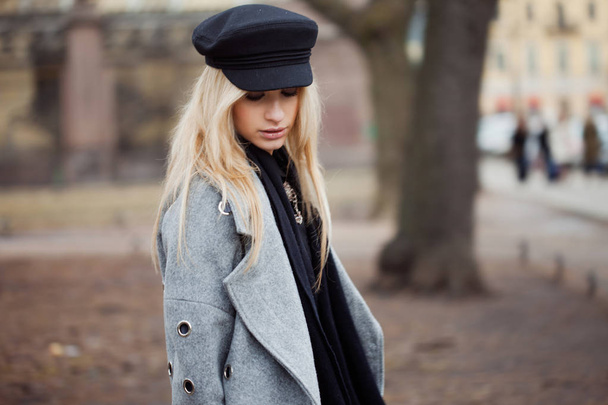 Young, hip and attractive blonde walking around the city, girl in a stylish hat and a gray coat - Photo, image