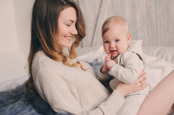 happy mother and baby playing at home in bedroom. Cozy family lifestyle in modern scandinavian interior.  - Foto, Imagem