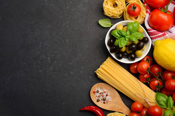 黒を背景にイタリア料理のパスタ、野菜、ハーブ、スパイス - 写真・画像