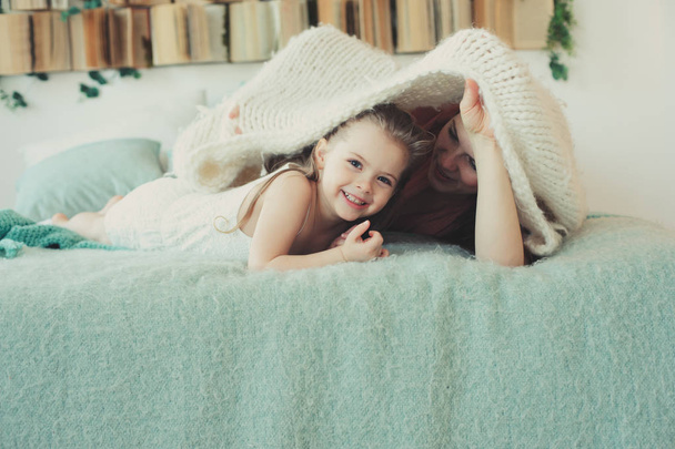 happy family playing at home. Mother and toddler daughter relaxing and having fun in bed in cozy weekend morning - Foto, Imagem