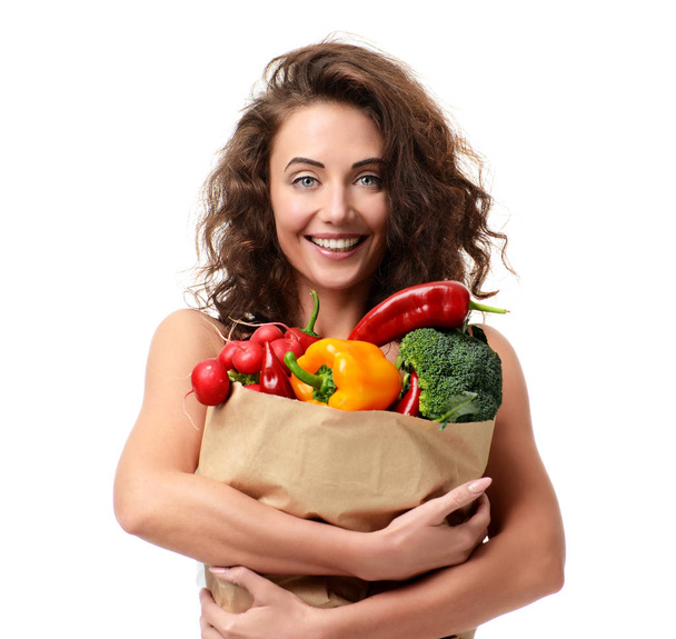 Young woman holding grocery paper shopping bag full of fresh veg - Fotó, kép