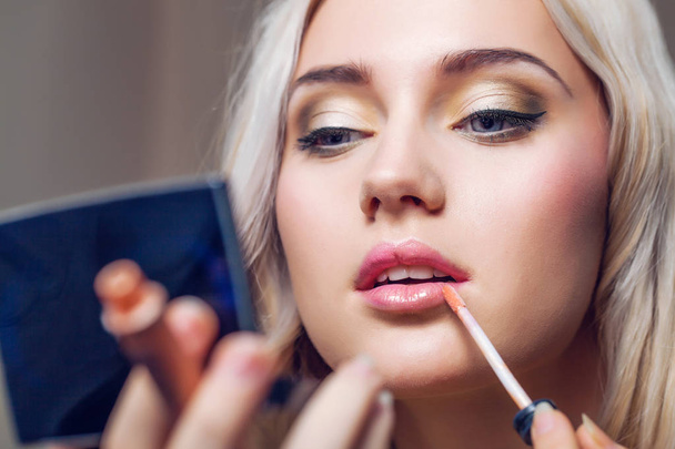 Beautiful young woman applying lips makeup with cosmetic brush - Foto, Bild