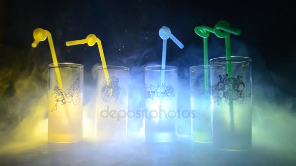 Fünf Cocktails an der Bar mit Rauch auf dunklem Hintergrund. gelbe, grüne und blaue Gläser. Club-Drinks - Filmmaterial, Video