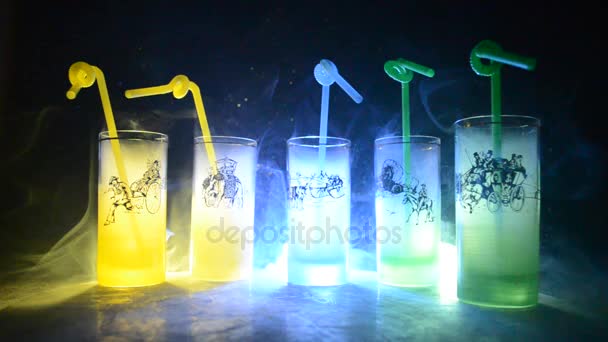 Vijf cocktails op de balk met rook op donkere achtergrond. Geel, groen en blauw gekleurde glazen. Club dranken - Video