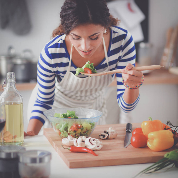 Young woman eating fresh salad in modern kitchen - Valokuva, kuva