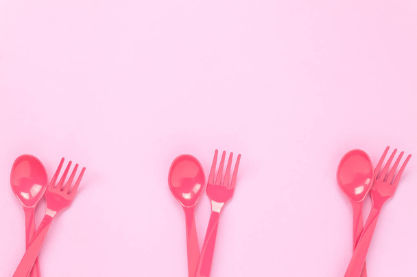 Vista superior colorida cuchara de plástico y tenedor en la mesa rosa
. - Foto, Imagen