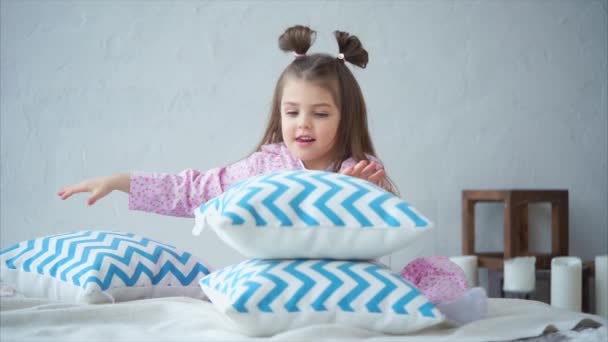 Egy kislány, ő haza pizsamában helyezi a piramis, a párnák a szobájában. - Felvétel, videó