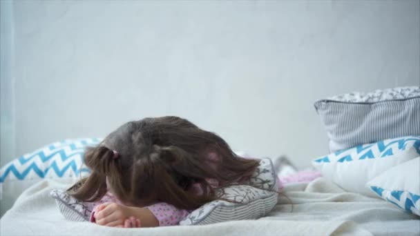 Édes boldog kis lány rózsaszín pizsama feküdt az ágyban, párnák. - Felvétel, videó