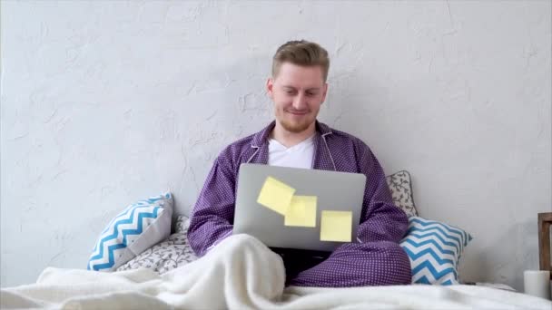 glücklicher Mann, der sich einen Film auf einem Laptop im Schlafzimmer ansieht - Filmmaterial, Video