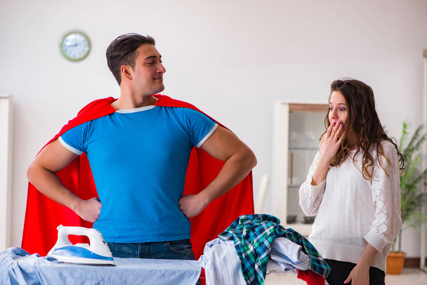 Super hero man husband ironing at home helping his wife - Photo, Image