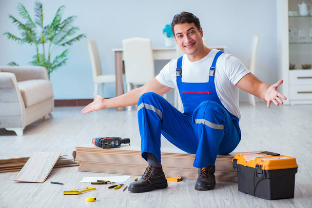 Repairman laying laminate flooring at home - Photo, Image