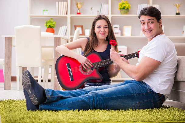 Romanttinen pari soittaa kitaraa lattialla - Valokuva, kuva