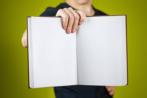 Closeup of guy in black t-shirt holding blank open white book on - 写真・画像