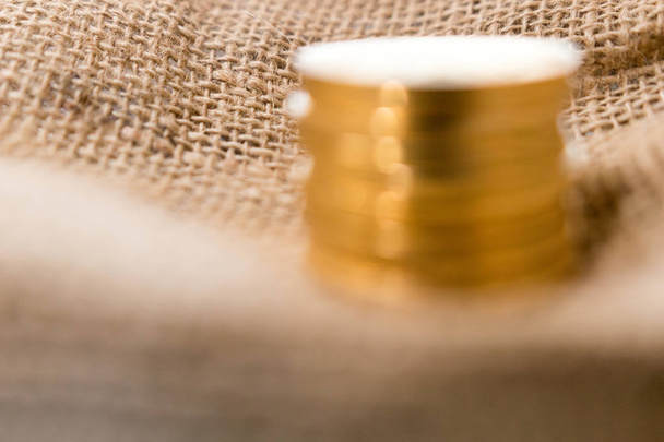 Stack of gold coins on jute background blurred  - Fotó, kép