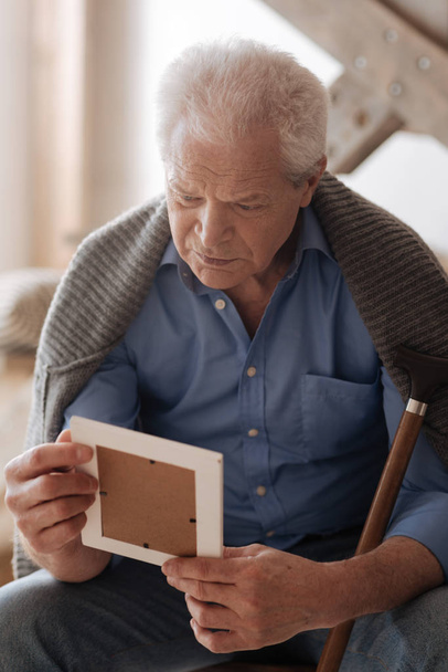 Sad elderly man holding a photo - Фото, изображение