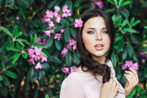 Outdoor fashion photo of beautiful young woman surrounded by flowers. Spring blossom - Φωτογραφία, εικόνα