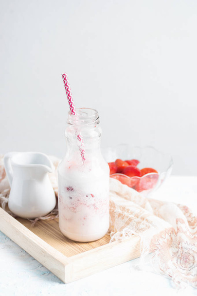Healthy strawberry milkshake in glass bottle with ingredients on - Photo, image